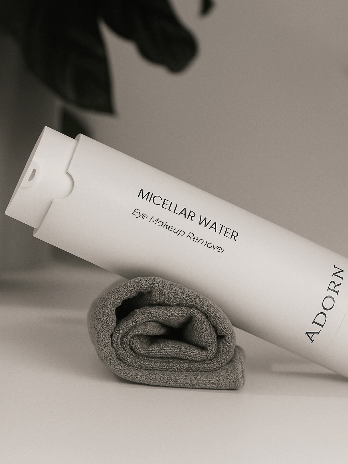ADORN Micellar Water Eye Makeup Remover bottle with a gray cloth on a neutral background