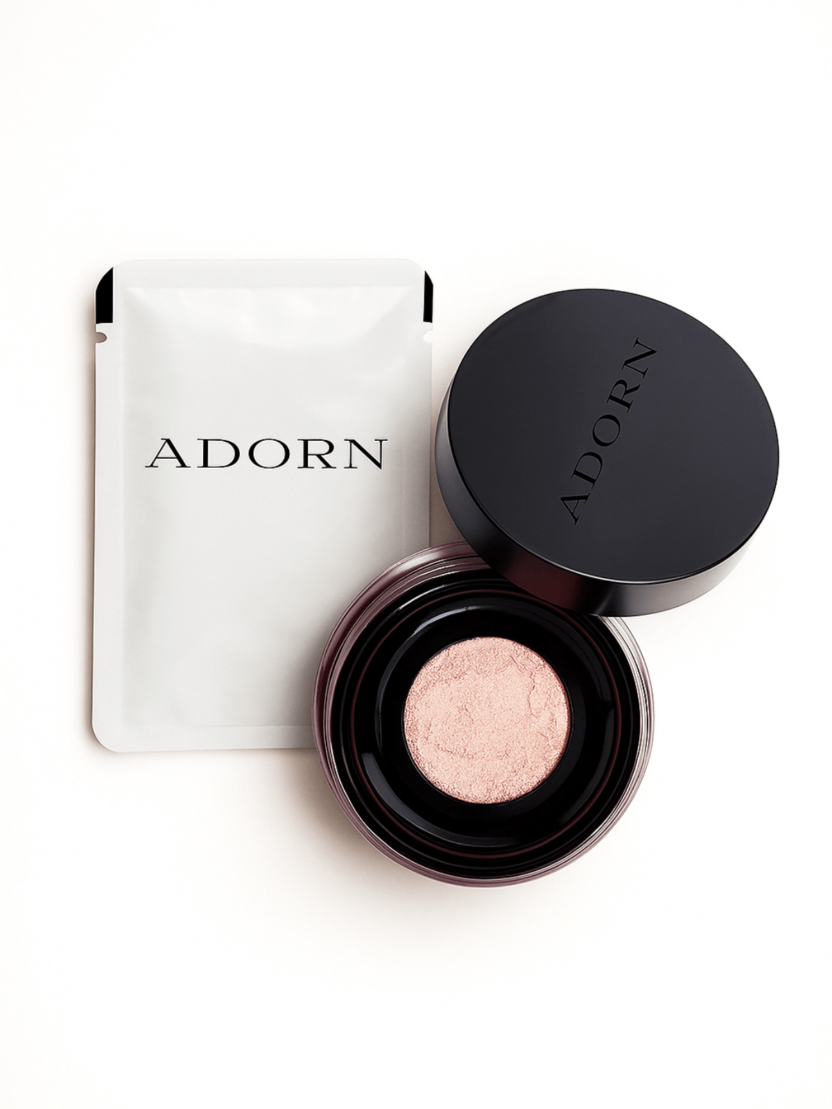 Open cosmetic container with pink powder and closed lid on a white background, branded 'Adorn'.