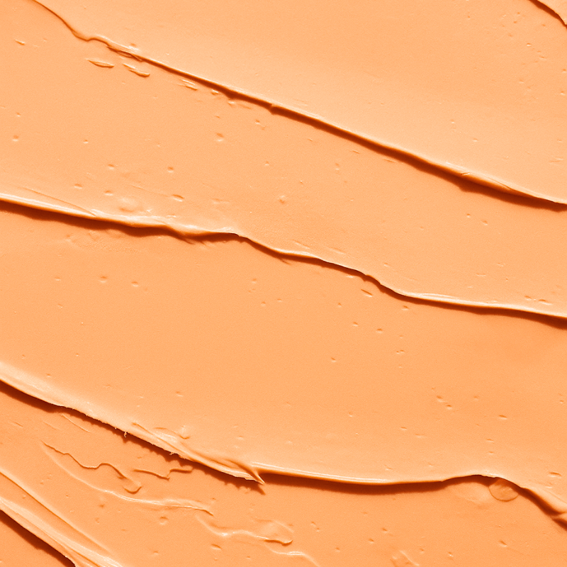 Close-up of peachy cream concealer for dark circles swatch with a textured surface