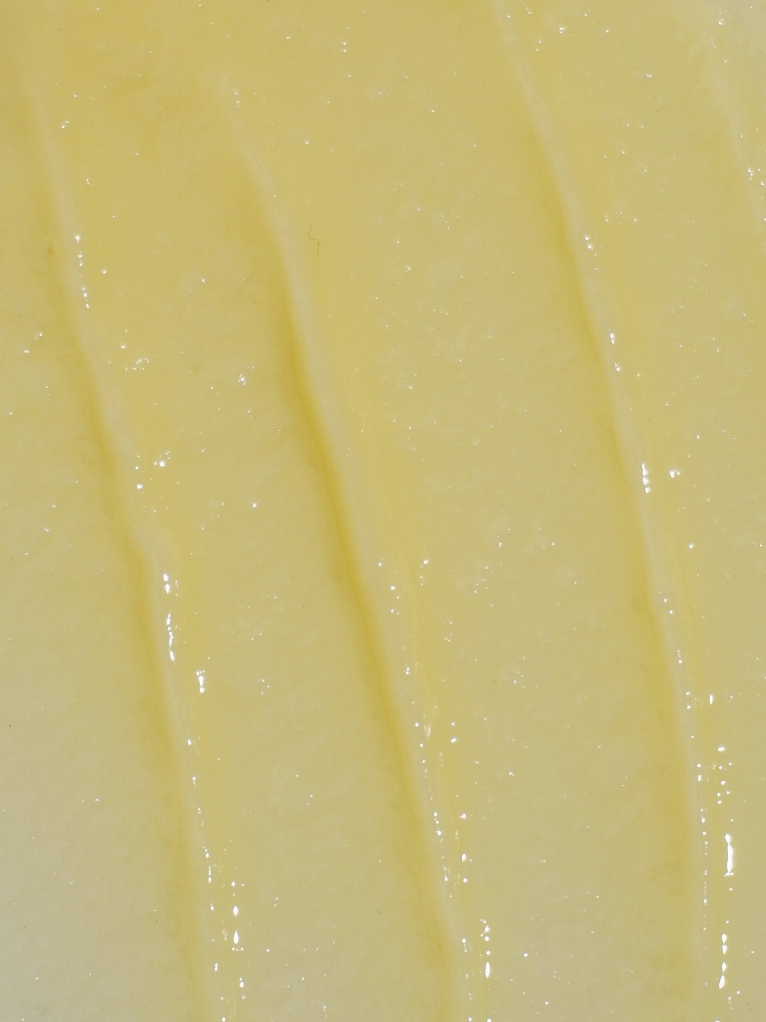 Close-up of a smooth, light yellow foot & heel balm texture
