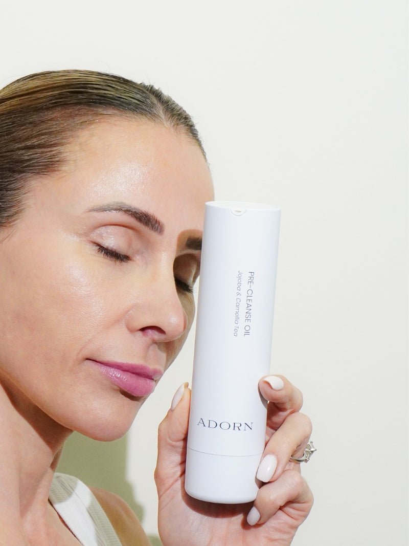 ADORN Camellia Makeup Removing Oil from Adorn Cosmetics held close to model's face.