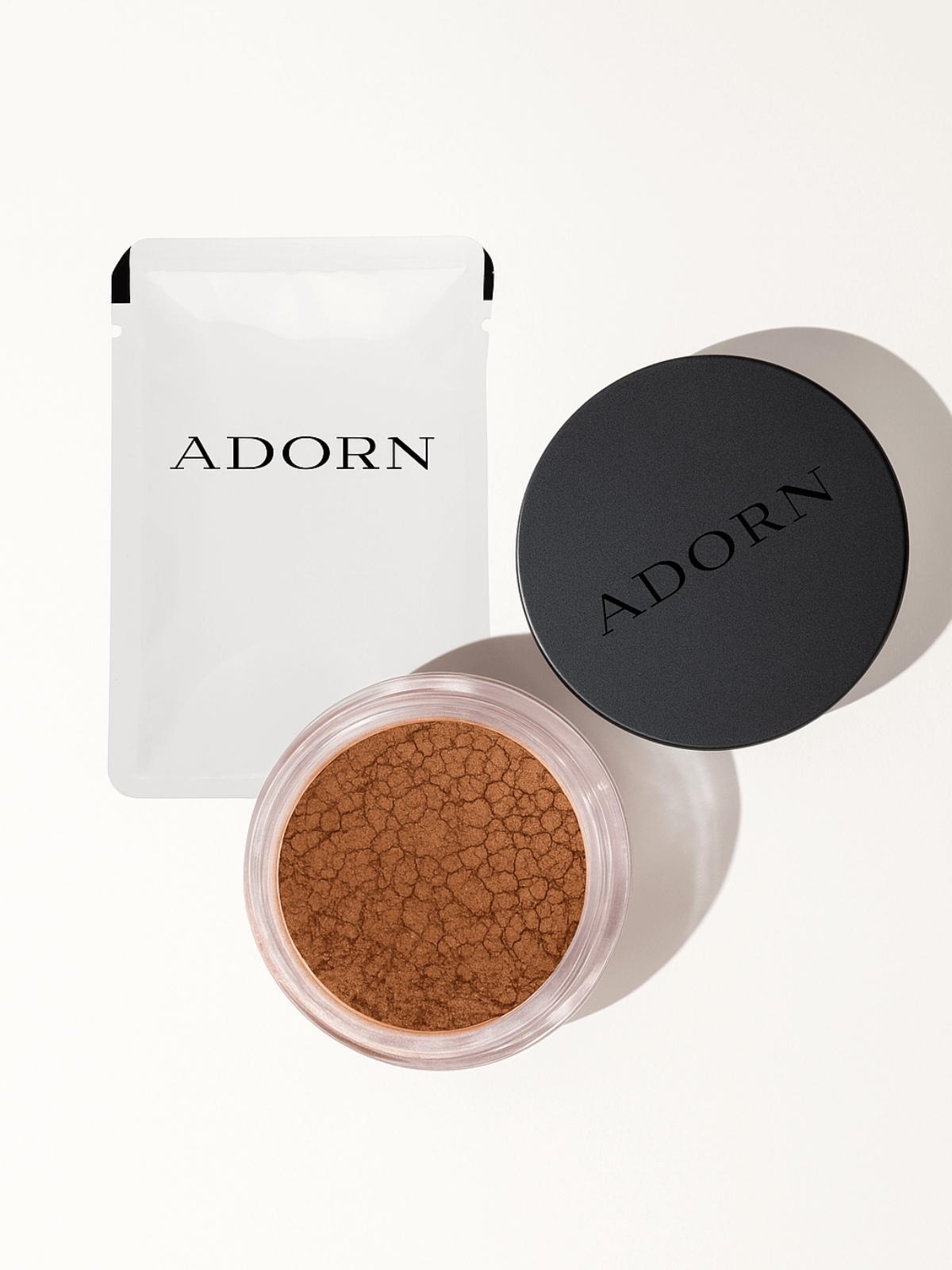 Open container of brown powder with 'ADORN' branding on a white background