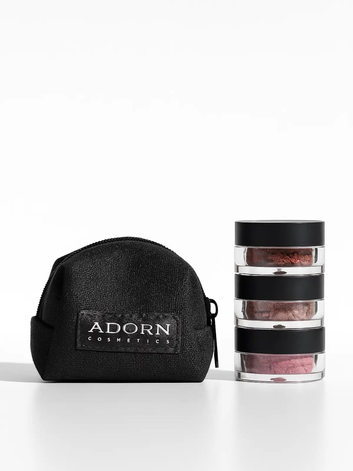 Black cosmetic bag with 'Adorn Cosmetics' logo and a stack of makeup containers on a white background.