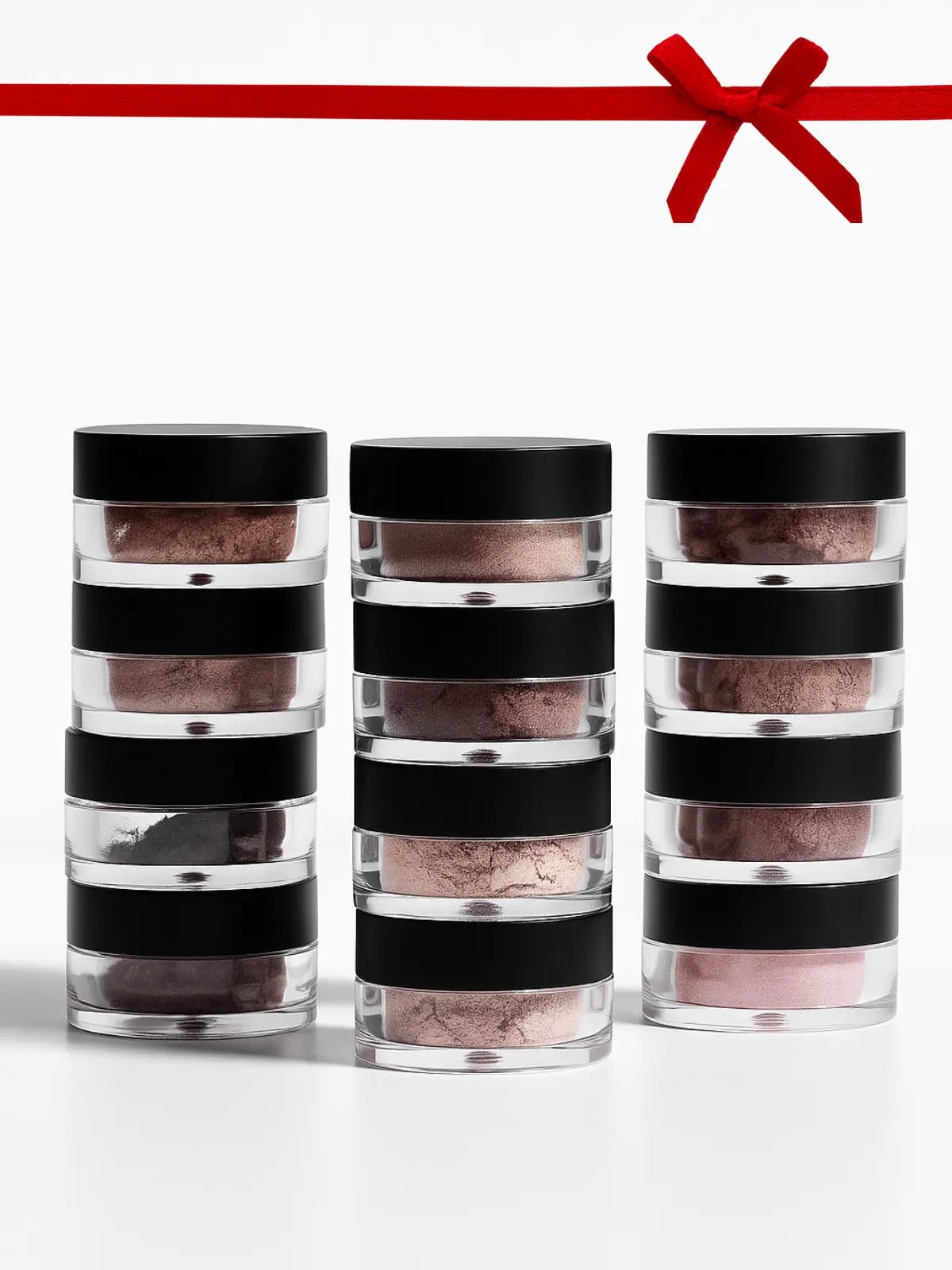 Three cylindrical containers with black lids stacked on a white background, with a red ribbon at the top.