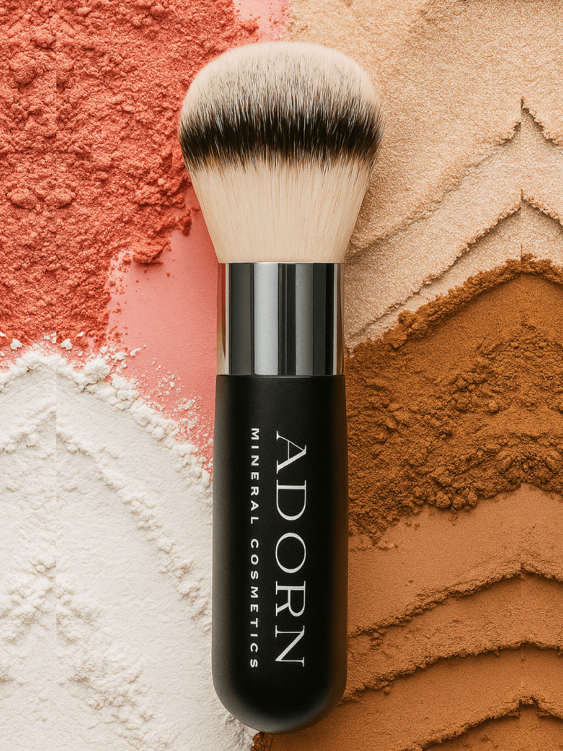 mineral powder brush with 'Adorn Mineral Cosmetics' on a colorful background of mineral powder.