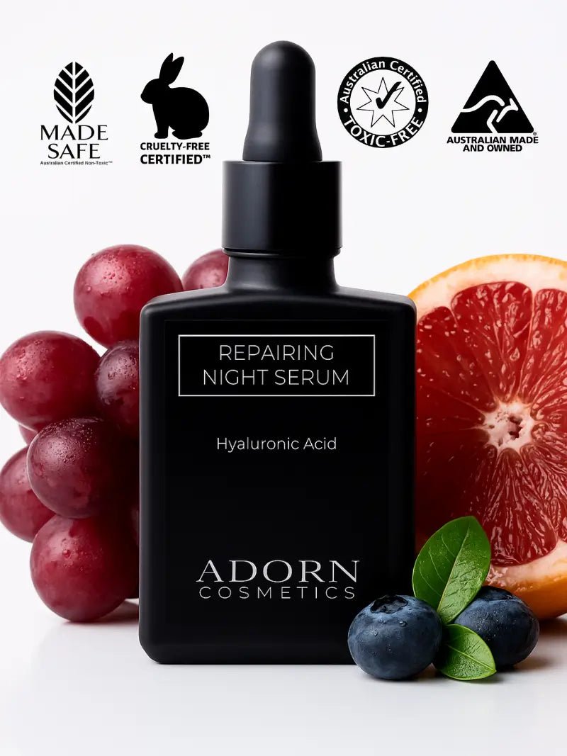 Black repairing night serum bottle with fruits and leaves on a white background, featuring Adorn Cosmetics branding.