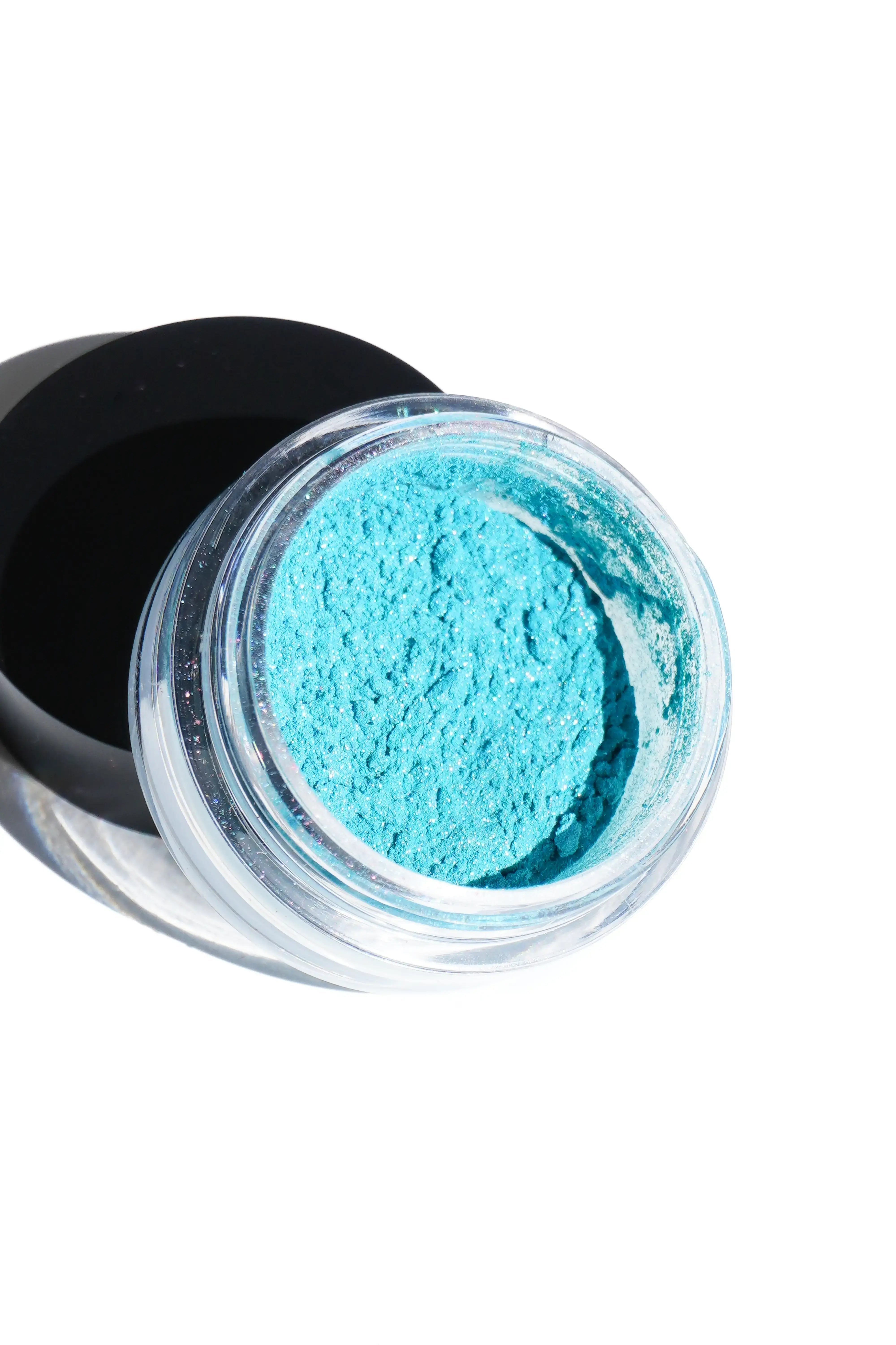 Open container of blue powder on a white background
