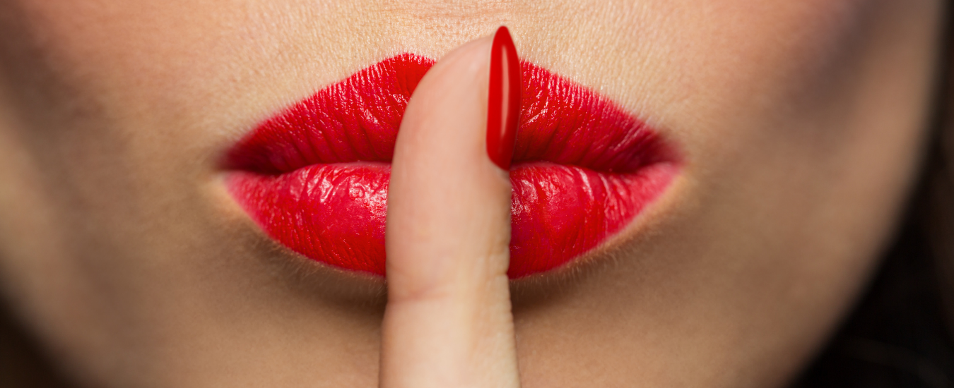 Close-up of red lipstick on lips with a finger touching the color.