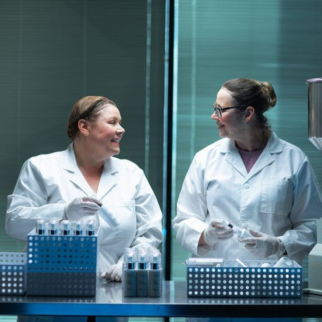 Two scientists in a laboratory filling adorn makeup.