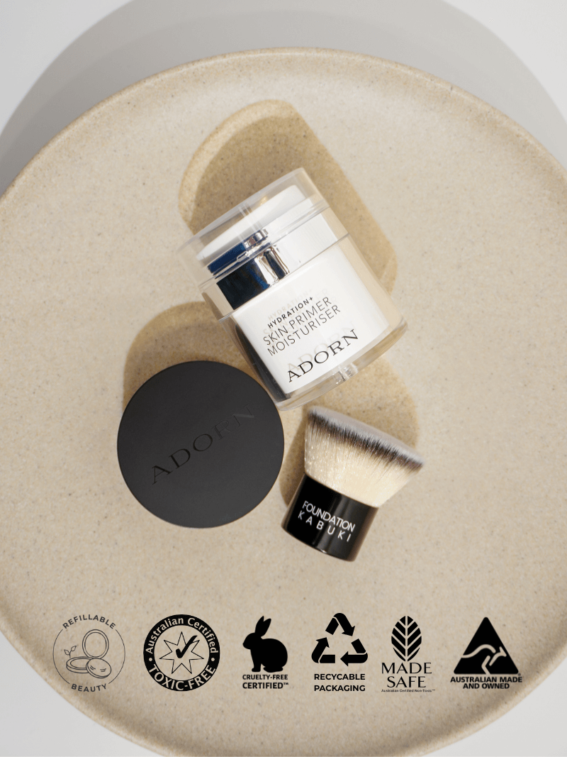 mineral makeup products including a jar, vegan makeup brush, and mineral foundation on a beige circular background with 'Adorn' branding.