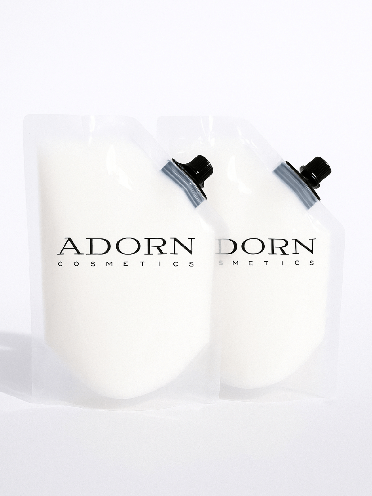 Two white refill pouches of Bulgarian rosewater with black caps labeled 'Adorn Dorn Cosmetics' on a white background.