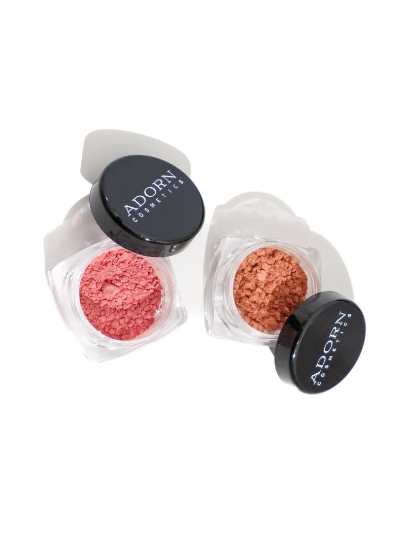 Two jars of cosmetic powders with 'Adorn' branding on a white background