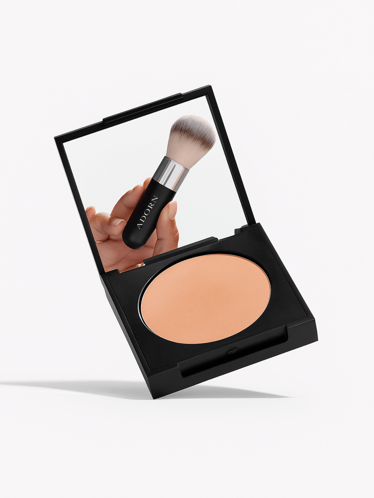 Makeup compact with a mirror showing a hand holding a brush, on a white background