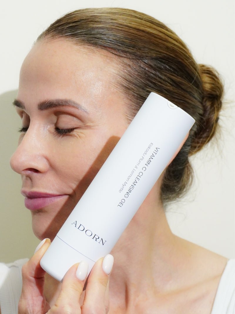 Face cleanser with vitamin c next to a mature woman's face.