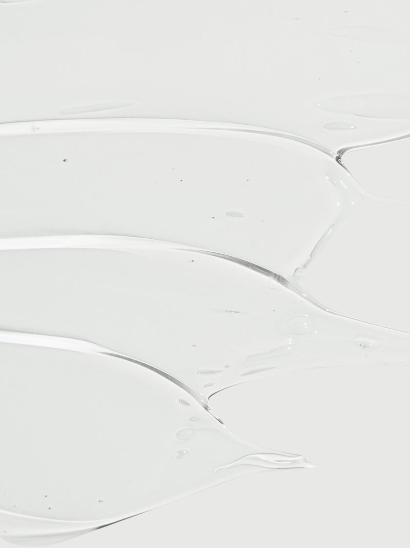 Gel texture of face cleanser with vitamin c on a gray background.