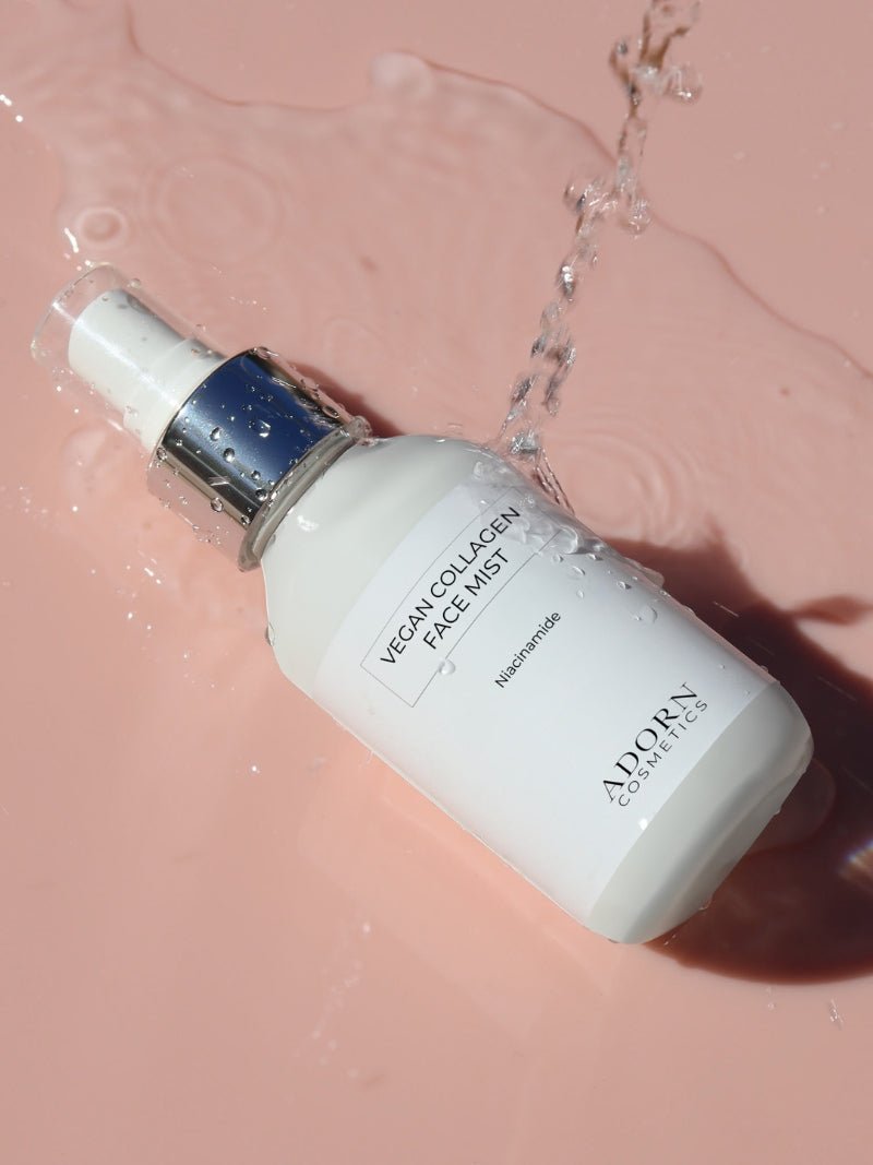 ADORN Niacinamide + Collagen Face Repair Mist for dry, mature skin on a pink background splashed by water.