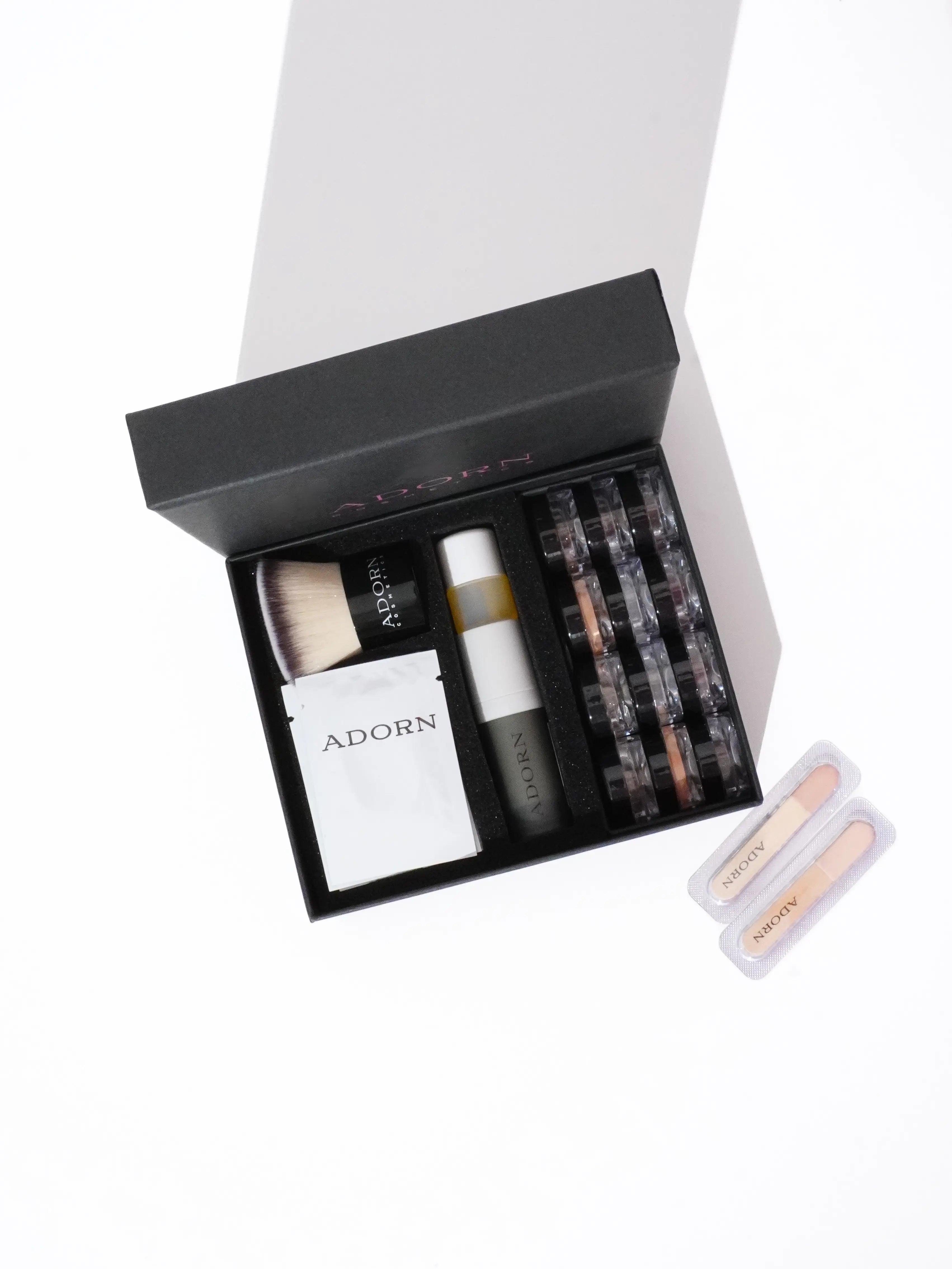 Adorn Cosmetics online foundation samples set including bottles, jars, and a box on a white background