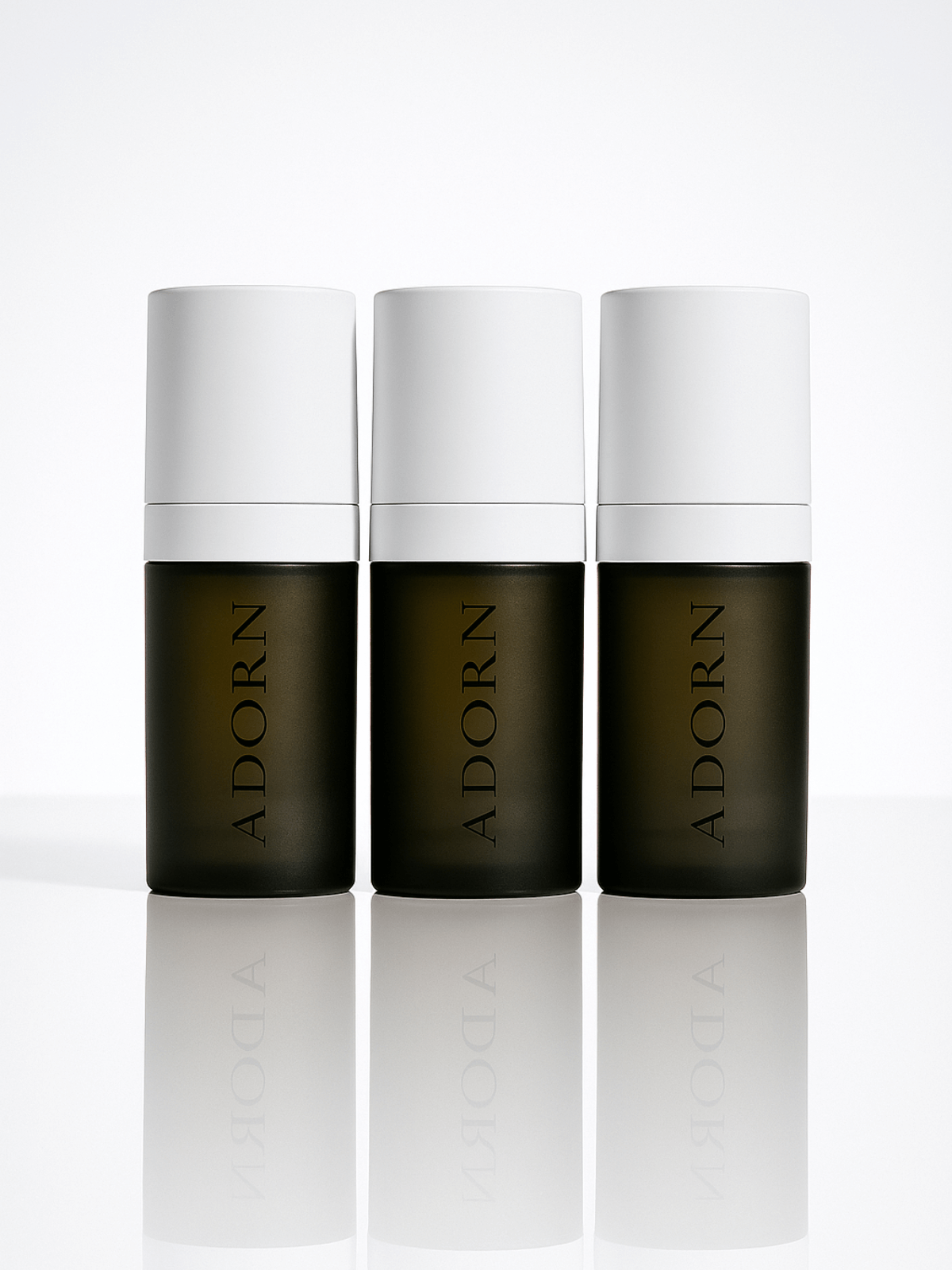 Three 'ADORN' skincare bottles on a white background