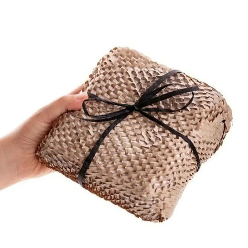 Hand holding a woven beige bag with a black ribbon on a white background