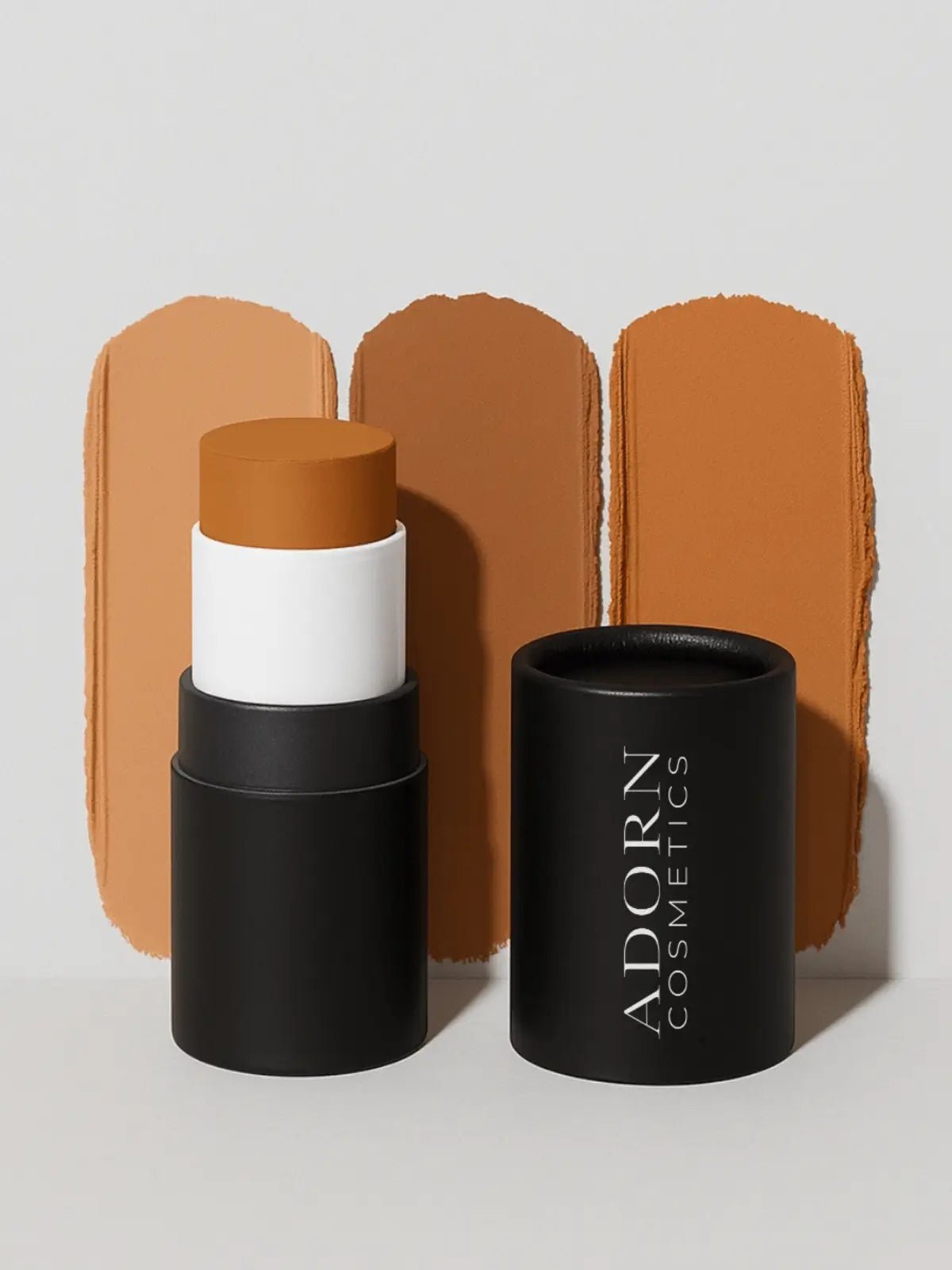 cream contour stick with black container labeled 'Adorn Cosmetics' on a light gray background