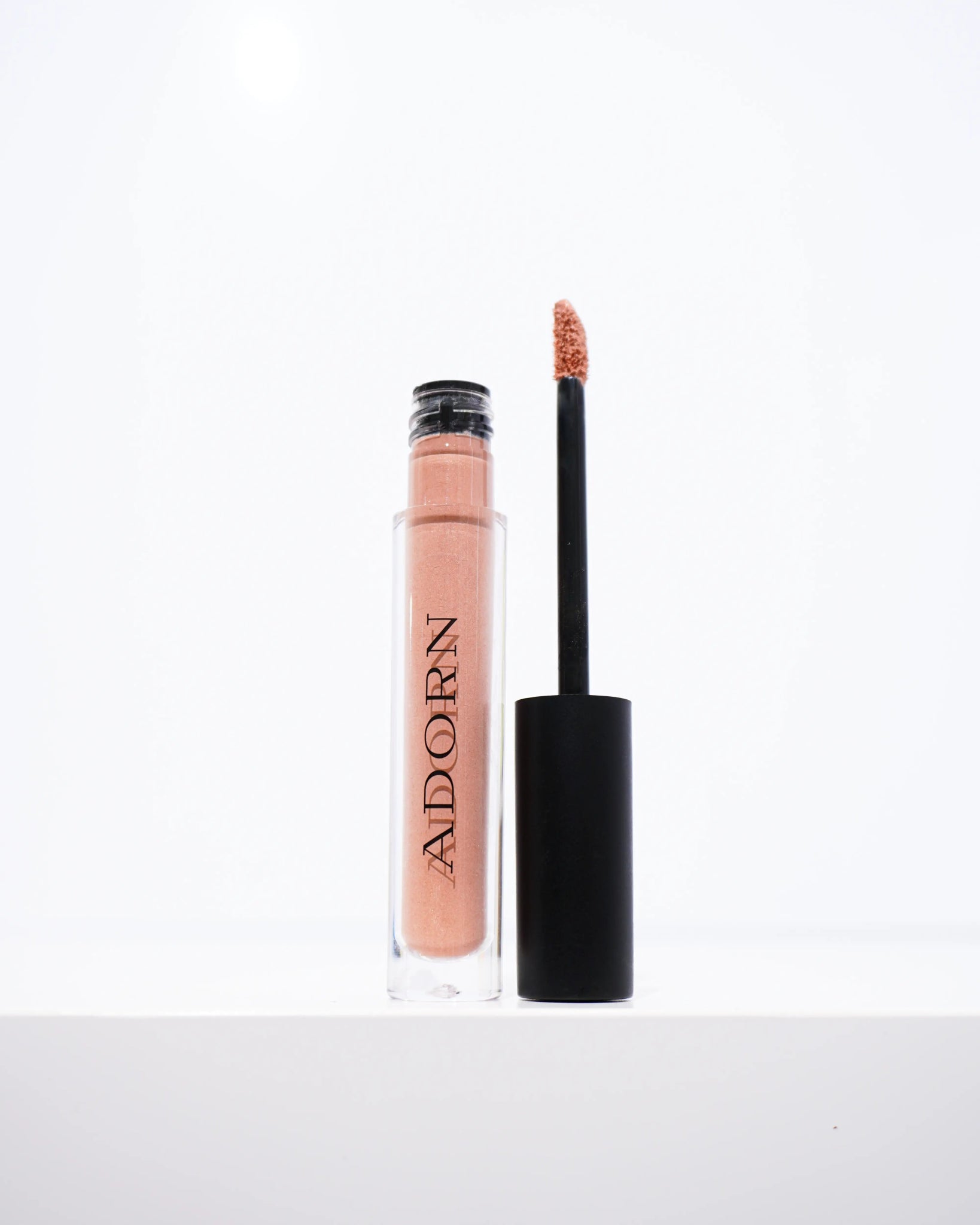 Liquid blush with applicator on a white background, featuring the brand 'Adorn'.