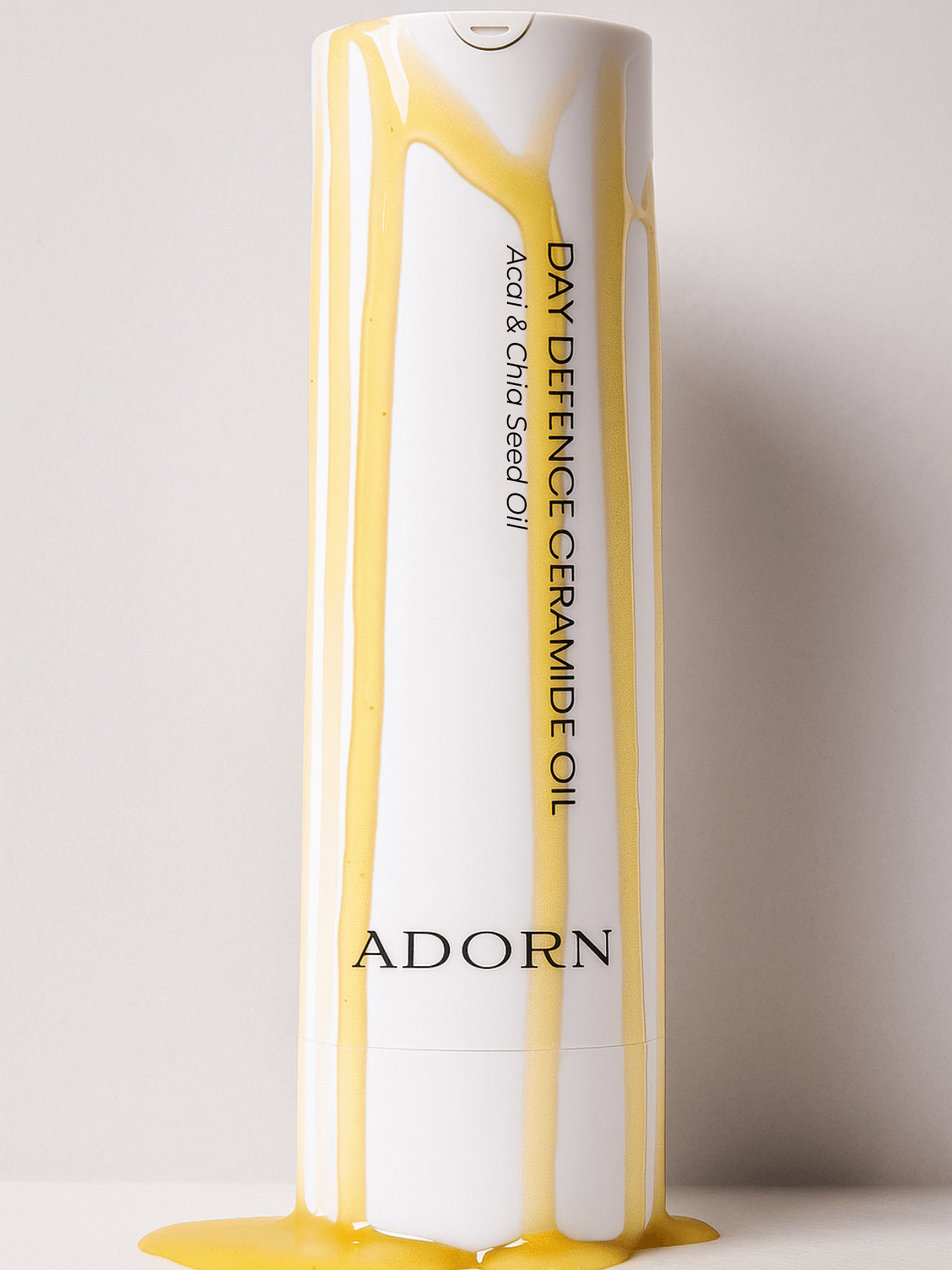 Adorn Day Defence Ceramide Oil bottle with yellow liquid on a light gray background